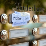Die Nachnamen von fünf Mietparteien stehen am Klingelschild einer Wohnung in einem Mehrfamilienhaus. 