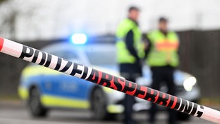 Eine Polizeiabsperrung mit Flatterband und Streifenwagen