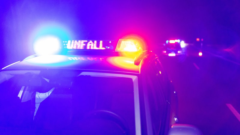 Ein Einsatzfahrzeug der Polizei steht mit Blaulicht und dem Schriftzug Unfall im Display auf einer Straße.