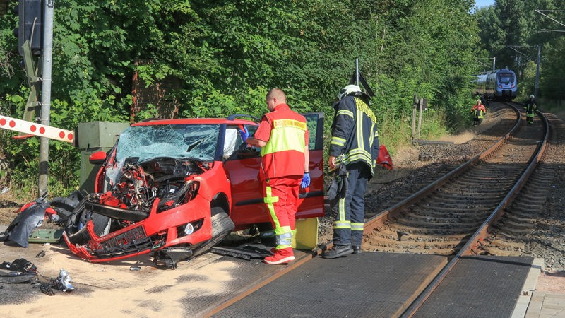 Ein zerstörtes Auto steht nach einem Unfall mit einem Zug auf einem Bahnübergang