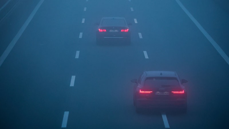 Zwei Autos fahren im Nebel über eine Autobahn