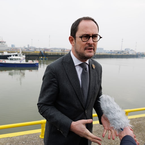 Belgiens Justizminister Vincent Van Quickenborne steht vor einem Hafen und wird interviewt.