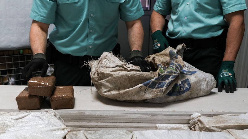 Zwei Zollbeamte holen Kokainpackungen aus einem präparierten Stapel Rigipsplatten in Bremen