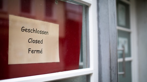 Geschlossen/Closed/Ferme steht an der Eingangstüre eines Cafés geschrieben. 