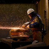 Ein Arbeiter flext ein fertiges Stahlbauteil 