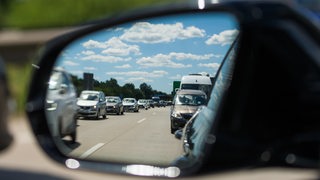 Blick in den Außenspiegel eines Autos, in dem zähfließender Verkehr auf der Autobahn A27 bei Bremerhaven zu sehen ist.