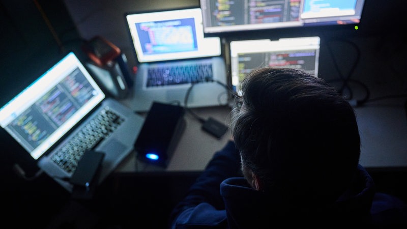 Ein Mann tippt im Dunkeln auf einer Computer-Tastatur