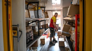 Ein Paketboten belädt sein Fahrzeug mit Kartons und Päckchen.
