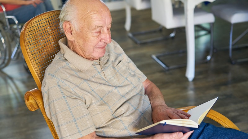 Senior im Ruhestand liest entspannt in einem Buch zu Hause oder in der Seniorenresidenz