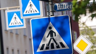 Drei Schilder signalisieren den Übergang für Fußgänger.