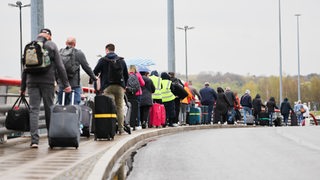 Fluggäste laufen am Hamburger Flughafen in einer langen Reihe zu einem Reisebus, der sie nach Bremen bringen soll.