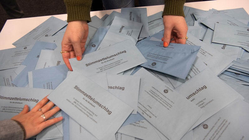Wahlhelfer sichten Stimmzettel von Briefwählern.