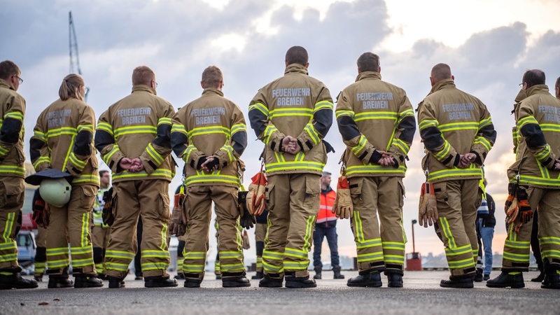 Bremer Feuerwehrleute stehen in einem Kreis und besprechen etwas.