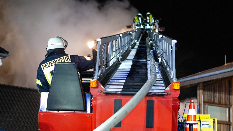 Feuerwehrleute löschen von einer Drehleiter einen Brand.