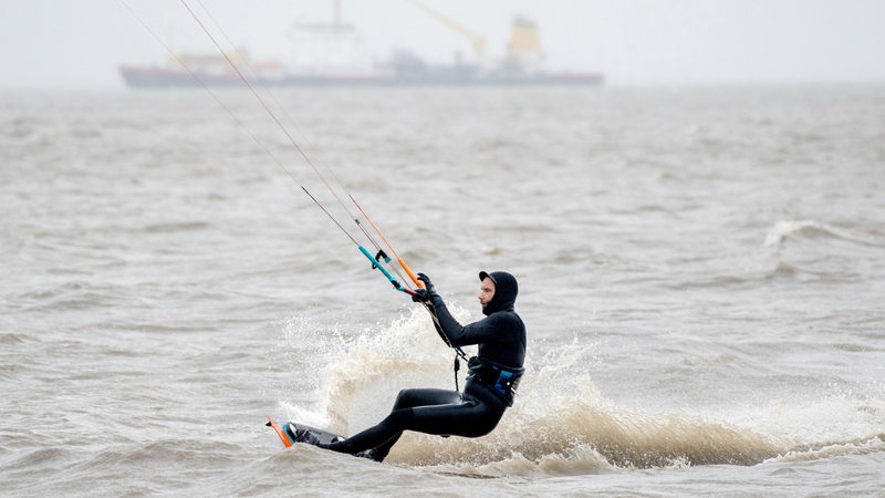 Ein Kitesurfer ist bei stürmischem Wetter auf der Nordsee unterwegs