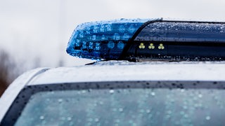 Auf einem Blaulicht eines Polizeiautos sind Regentropfen zu sehen.