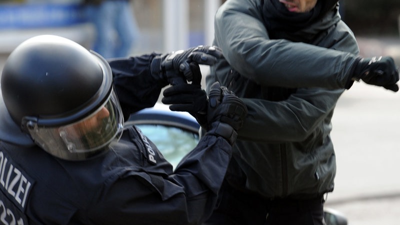 Ein gewalttätiger Demonstrant schlägt einen Polizeibeamten nieder.