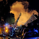 Feuerwehrleute löschen von einer Drehleiter aus ein Feuer auf einem Fabrikgelände.