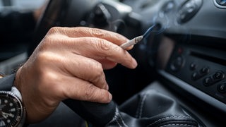 Ein Mann raucht in einem Auto.