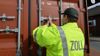 Ein Mitarbeiter des Zolls öffnet einen Container.