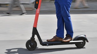 Ein Mann steht auf einem elektrischen Tretroller.