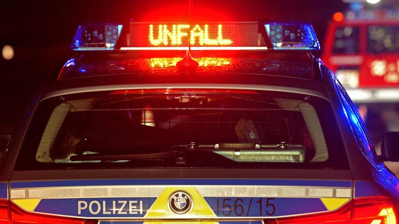 Ein Polizeiwagen steht in der Dunkelheit, das Wort Unfall leuchtet in LED-Schrift auf seinem Dach. (Symbolbild)