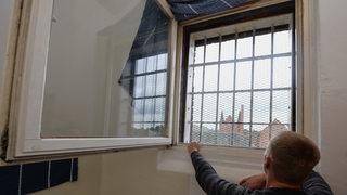 Häftling schaut aus durch die Gitter seines Fensters