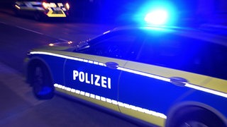 Ein Polizeiwagen fährt im Dunklen mit Blaulicht