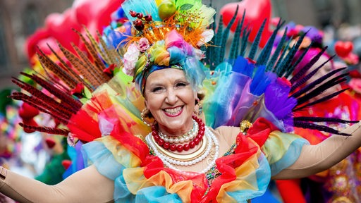  Akteure des Samba-Karnevals-Umzuges ziehen in bunten Kostümen durch die Innenstadt.