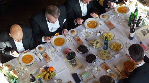 Männer in Smokings essen Suppe