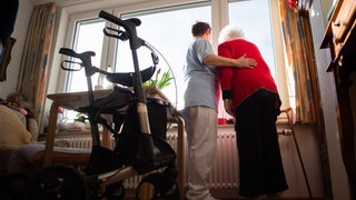 Mitarbeiterin in einem Pflegeheim mit Seniorin