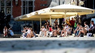 Zahlreiche Menschen sitzen in der Innenstadt auf den Treppen am Rathausmarkt in Oldenburg, wo sonst die Tische und Stühle der Gastronomie unter Schirmen stehen. Ab dem 11.05. dürfen Restaurants, Gaststätten und Cafés in Niedersachsen unter Auflagen wieder öffnen. 