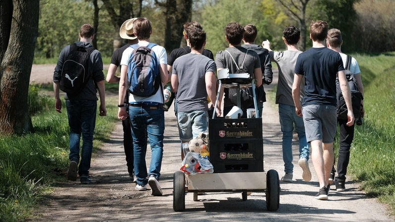 Eine Gruppe von Männern sind mit einem Bollerwagen unterwegs, auf dem Bier transport wird (Symbolbild)