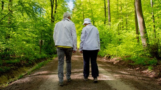 Ein Ehepaar läuft auf einem Waldweg.