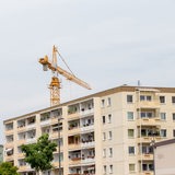 Ein Kran ist über einem mehrstöckigem Wohngebäude zu sehen.