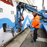 Ein Mann steht vor einem Landstromanschluss an einem Schiff.