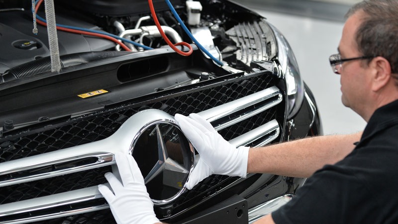 Ein Mitarbeiter von Mercedes-Benz bringt im Werk in Bremen den Stern an ein C-Klasse Modell.