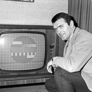 Ein Mann kniet vor seinem Fernseher, auf dem ein Schwarzweiß-Testbild zu sehen ist (Archivbild)