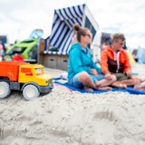 Ein Spielzeug-LKW steht im Sand vor dem Strandkorb einer Familie am Nordstrand Norderney.