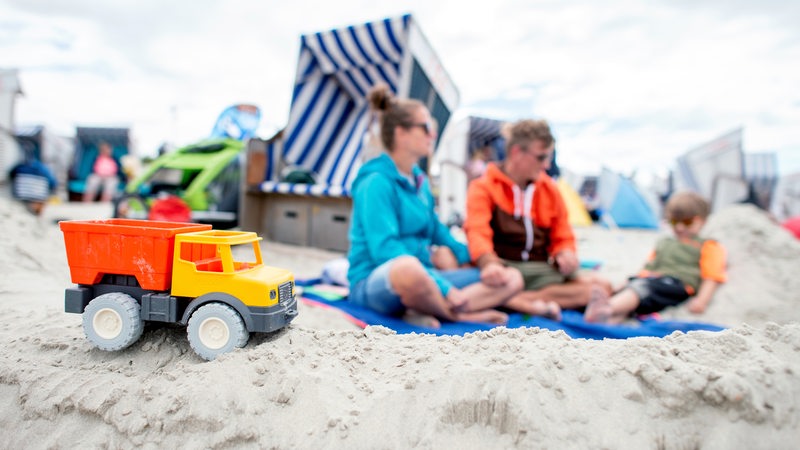 Ein Spielzeug-LKW steht im Sand vor dem Strandkorb einer Familie am Nordstrand Norderney.