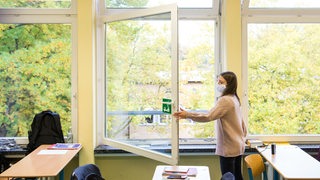 Eine Schülerin einer Oberstufe öffnet das Fenster zum Lüften. (Symbolbild)