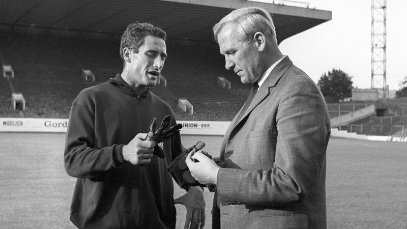 Fußball-WM 1966 - Der deutsche Nationaltorwart Hans Tilkowski (l) und der ehemalige deutsche Torwart Bert Trautmann unterhalten sich während des Trainings in Sheffield.
