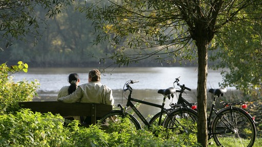 Ein Mann und eine Frau sitzen auf einer Parkbank.