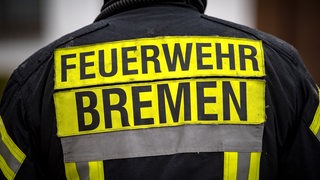 Feuerwehrmann mit dem Schriftzug "Feuerwehr Bremen" auf dem Rücken.