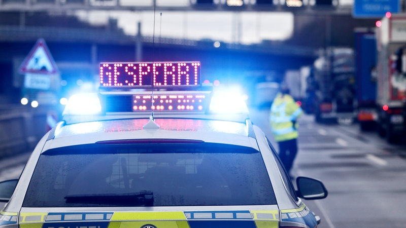 Ein Polizeiauto steht auf einer Autobahn. Auf dem Dach leuchtet auf einer Anzeige die Aufschrift "Gesperrt".