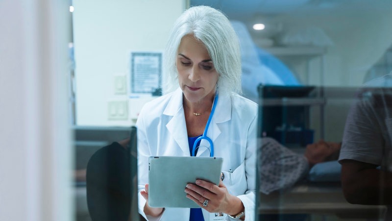 Eine Ärztin studiert Patientenunterlagen auf einem Tablett-PC.