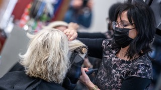 Eine Friseurin schneidet einer Frau in einem Friseursalon die Haare.