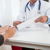 Ein Arzt unterhält sich in einer Arztpraxis mit einer Patientin.