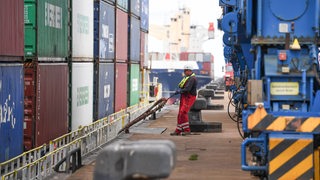 Ein Mann löst am Bremerhavener Containerterminal die Taue eines Schiffes, das ablegt. 