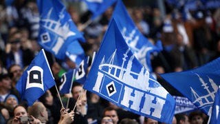 Fans des Hamburger SV schwenken blau-weiße Fahnen mit der HSV-Raute.